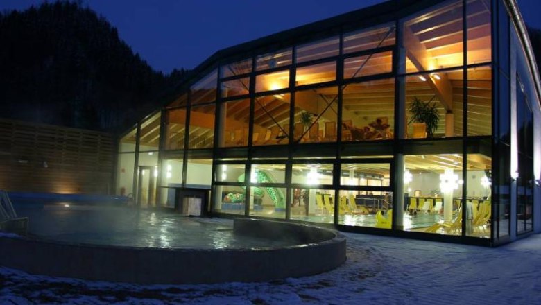 Exterior view of the Ybbstaler Solebad Göstling at night with illuminated indoor area.