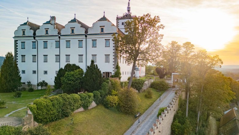 Weitra Castle at sunset with garden and trees in the foreground.