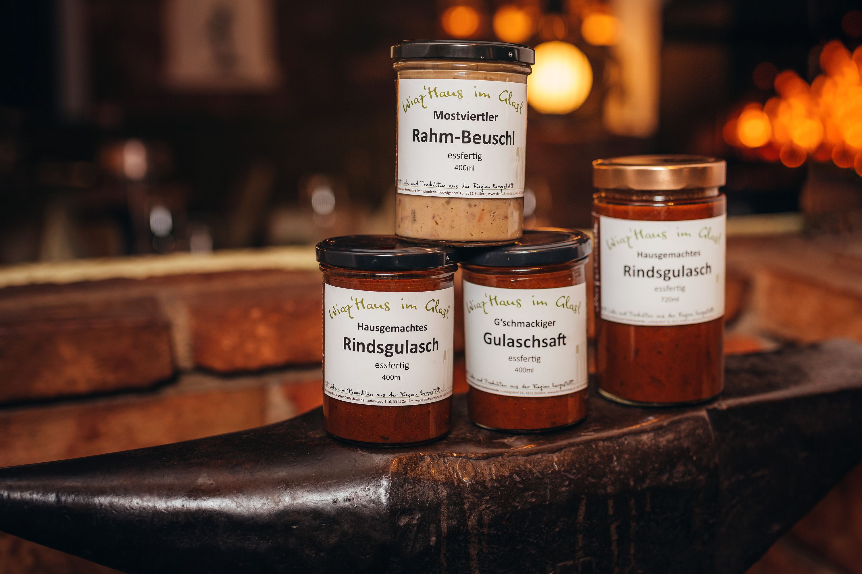Three jars of ready meals on an anvil, labeled 'Wirtshaus im Glas'.