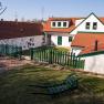 A traditional vineyard with red tiled roofs, green fences and garden furniture on a meadow.