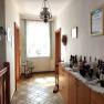 A bright anteroom with tiled floor, a chest of drawers with wine bottles and a window with curtains.