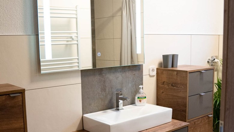 Modern bathroom with wooden cabinets, washbasin and mirror.