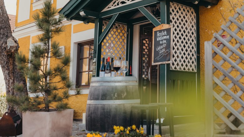Entrance of a pub with wine barrel, glasses and flowers.