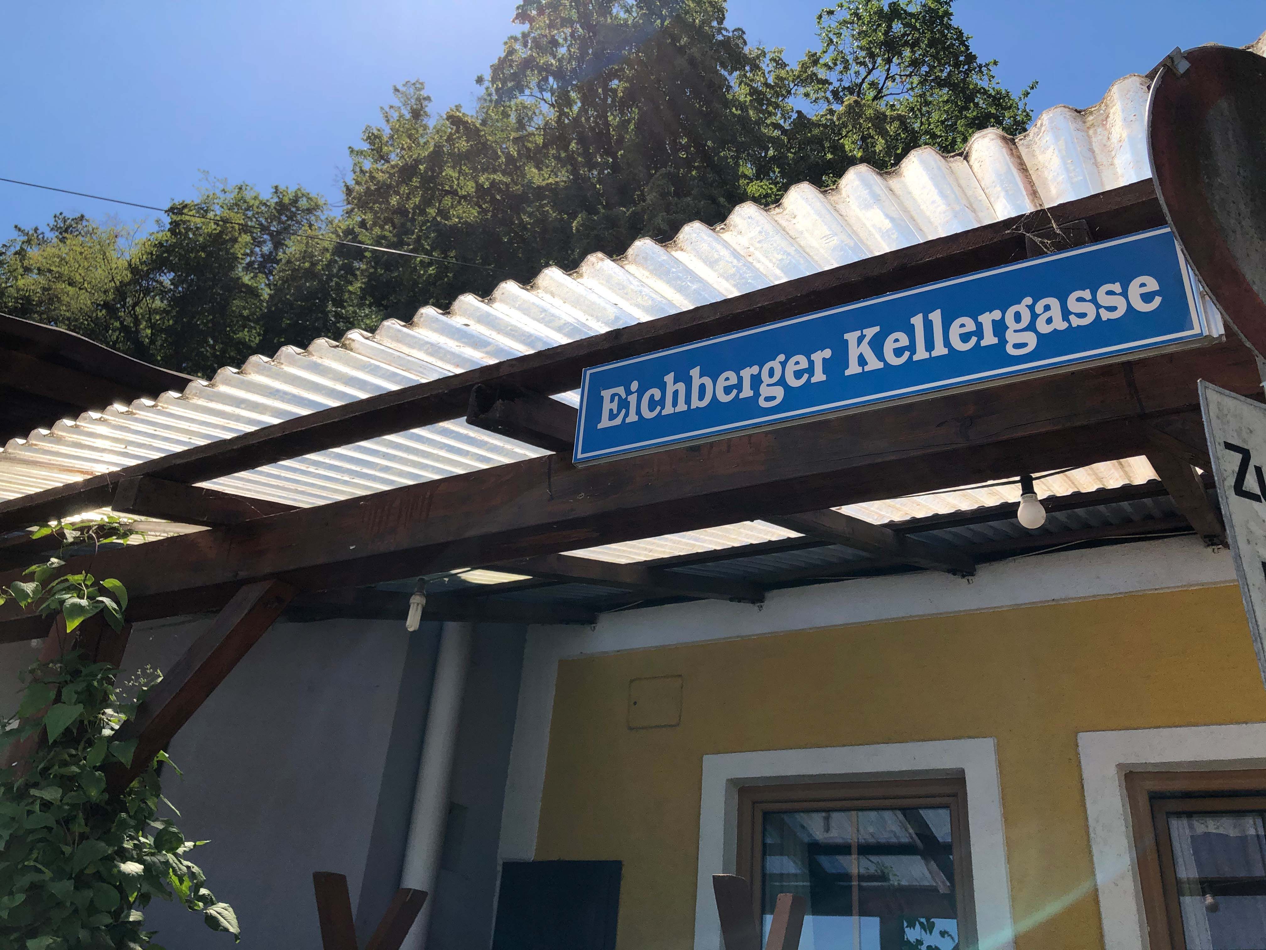 Sign with the inscription 'Eichberger Kellergasse' on a building with a corrugated iron roof.