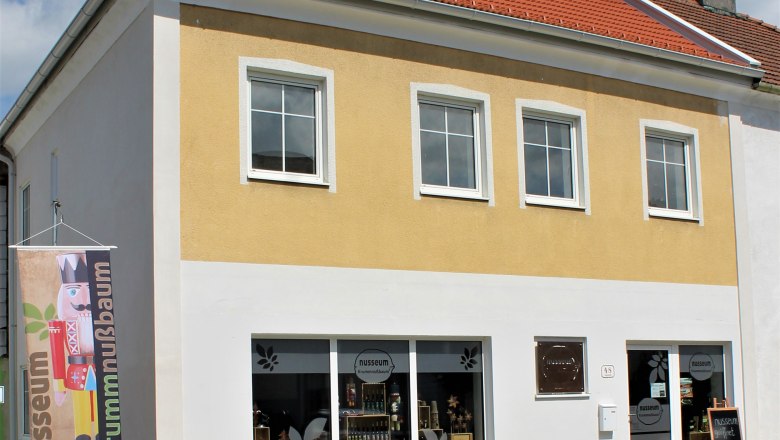 Exterior view of the Nusseum in Krummnussbaum with yellow façade and shop windows.
