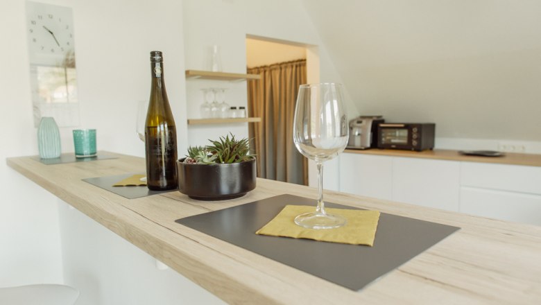 Modern kitchen with bar counter, wine glass and bottle.