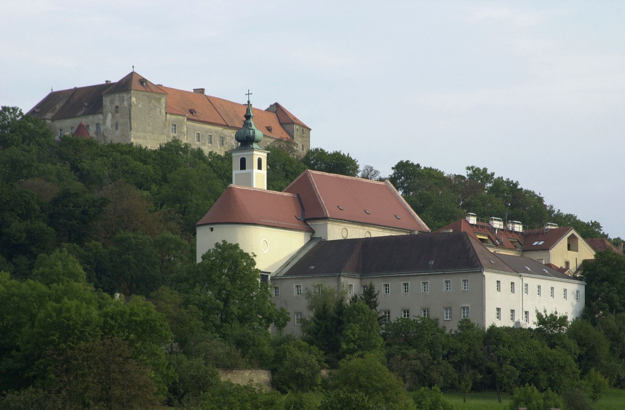 Neulengbach Castle on a hill with surrounding buildings and trees.