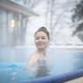 Woman in the outdoor pool in cold weather, surrounded by steam.