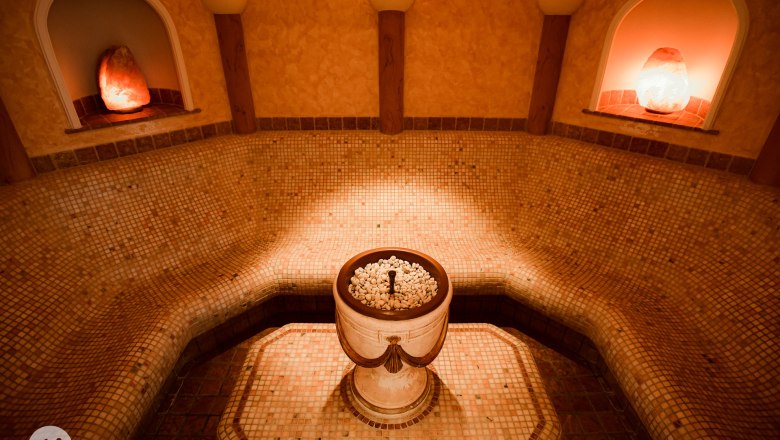 A laconium with mosaic tiles, a central fountain and warm light.