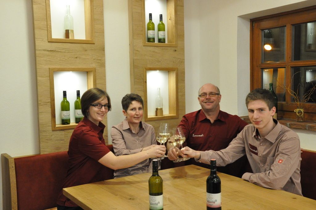 Four people clink glasses of wine at a table.
