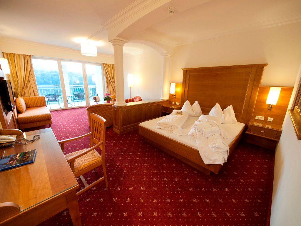 Hotel room with double bed, desk and balcony with view.