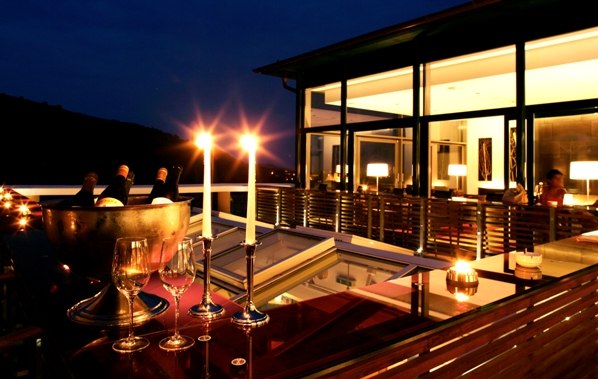 Evening restaurant terrace with candlelight and wine glasses.