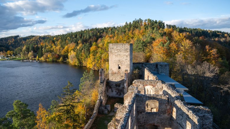 Dobra ruins with a view of a lake and autumnal forest.