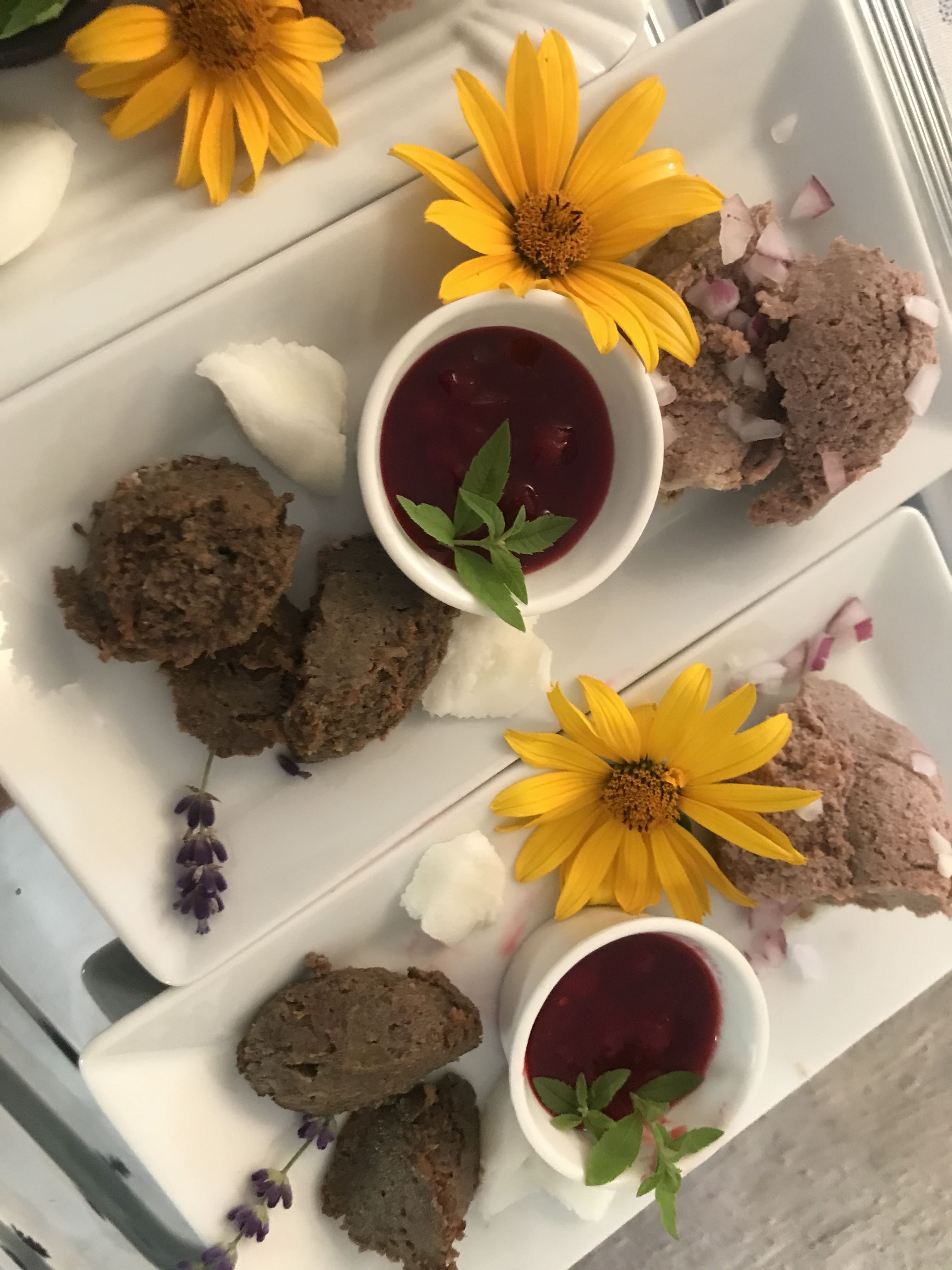 Plates with spreads, yellow flowers and red sauces in small bowls.