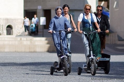 People ride three-wheeled scooters in Mariazell.