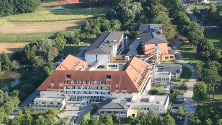 Aerial view of a clinic with red roofs, surrounded by trees and fields.