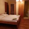 A simply furnished hotel room with a double bed, wooden floor and small bathroom.