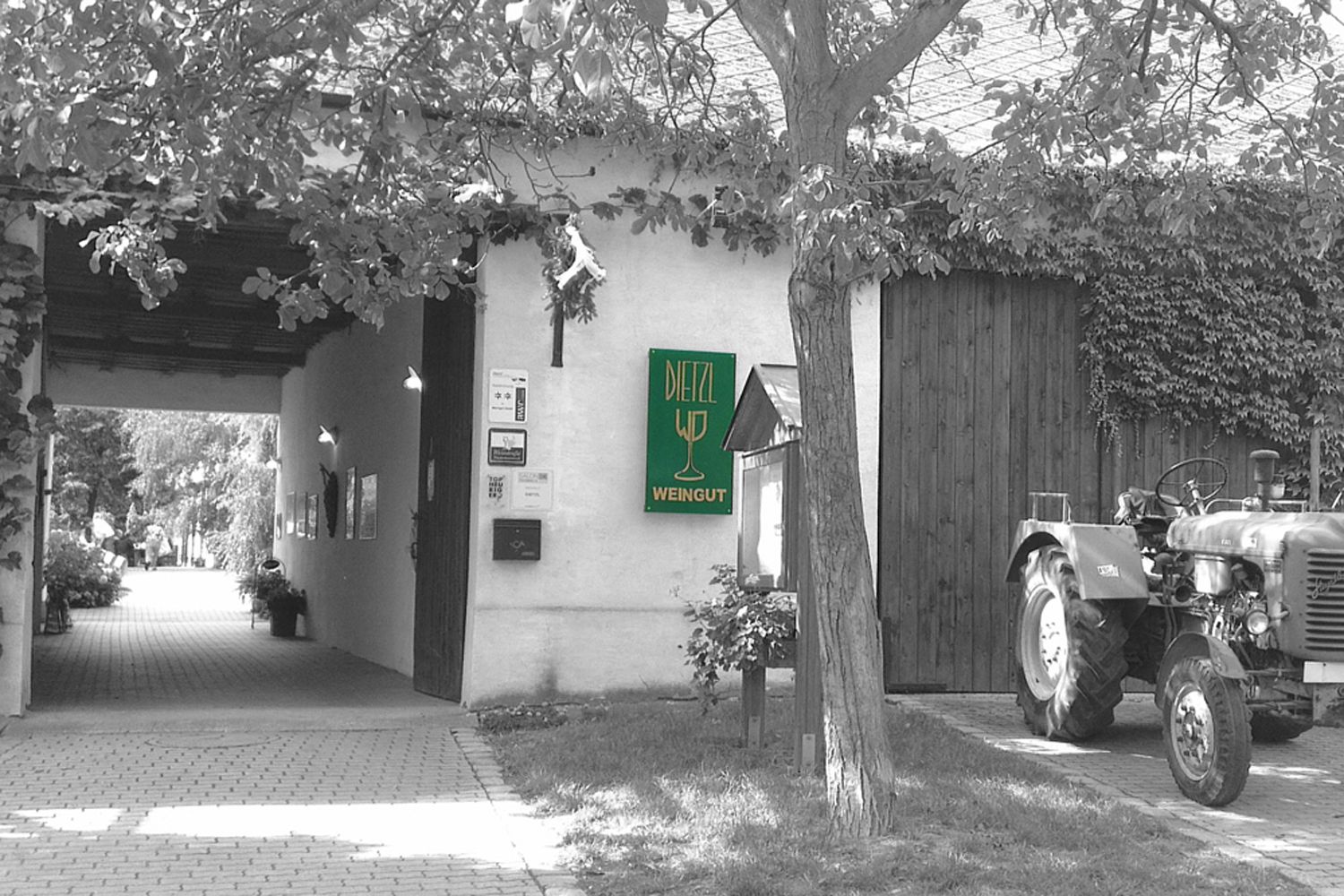 Entrance of a winery with a sign 'Dietzl Weingut' and a tractor next to it.