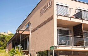Modern building of the Stadler winery with terrace and castle in the background.