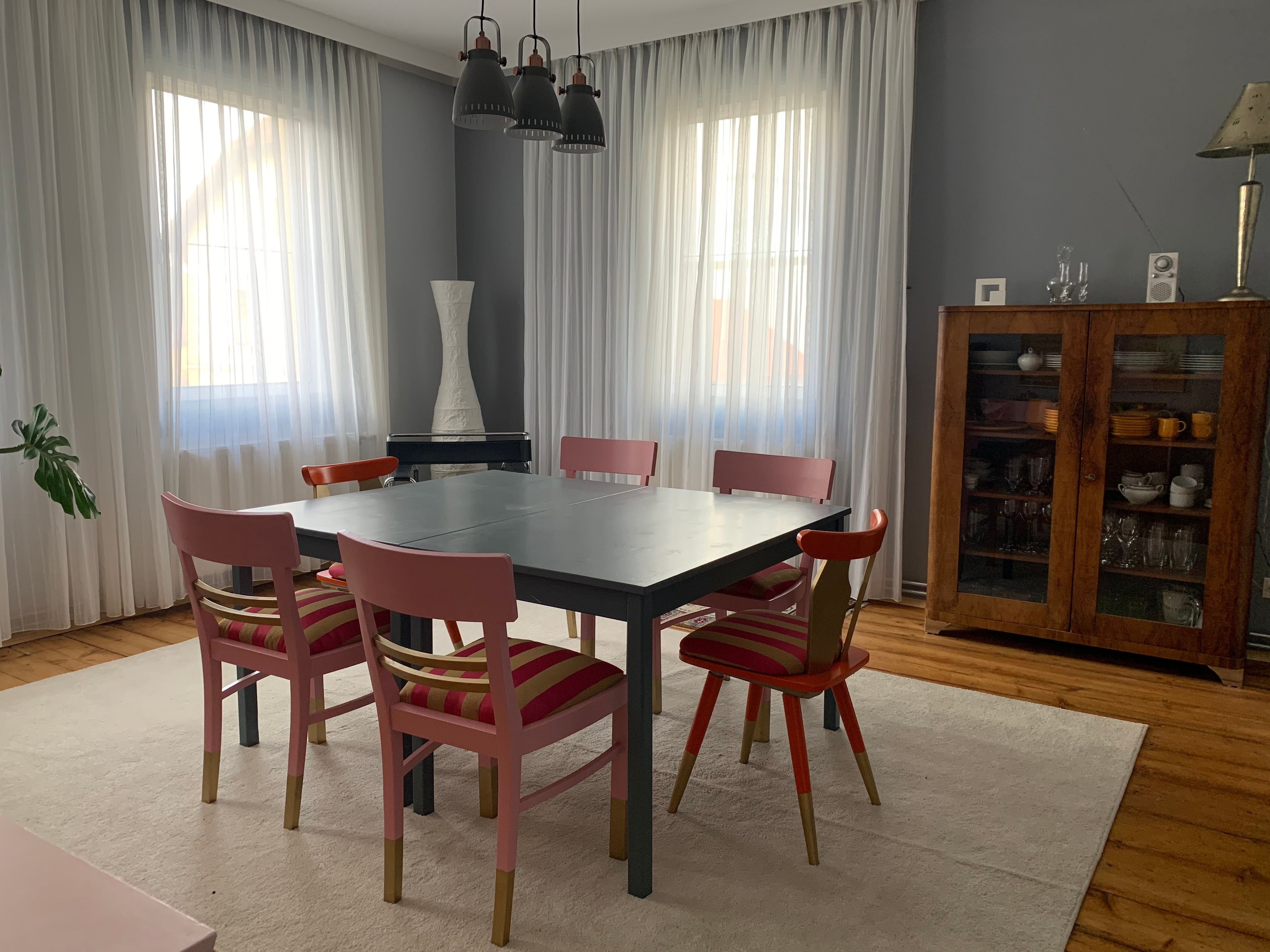 Dining room with table, six chairs, display cabinet and curtains.