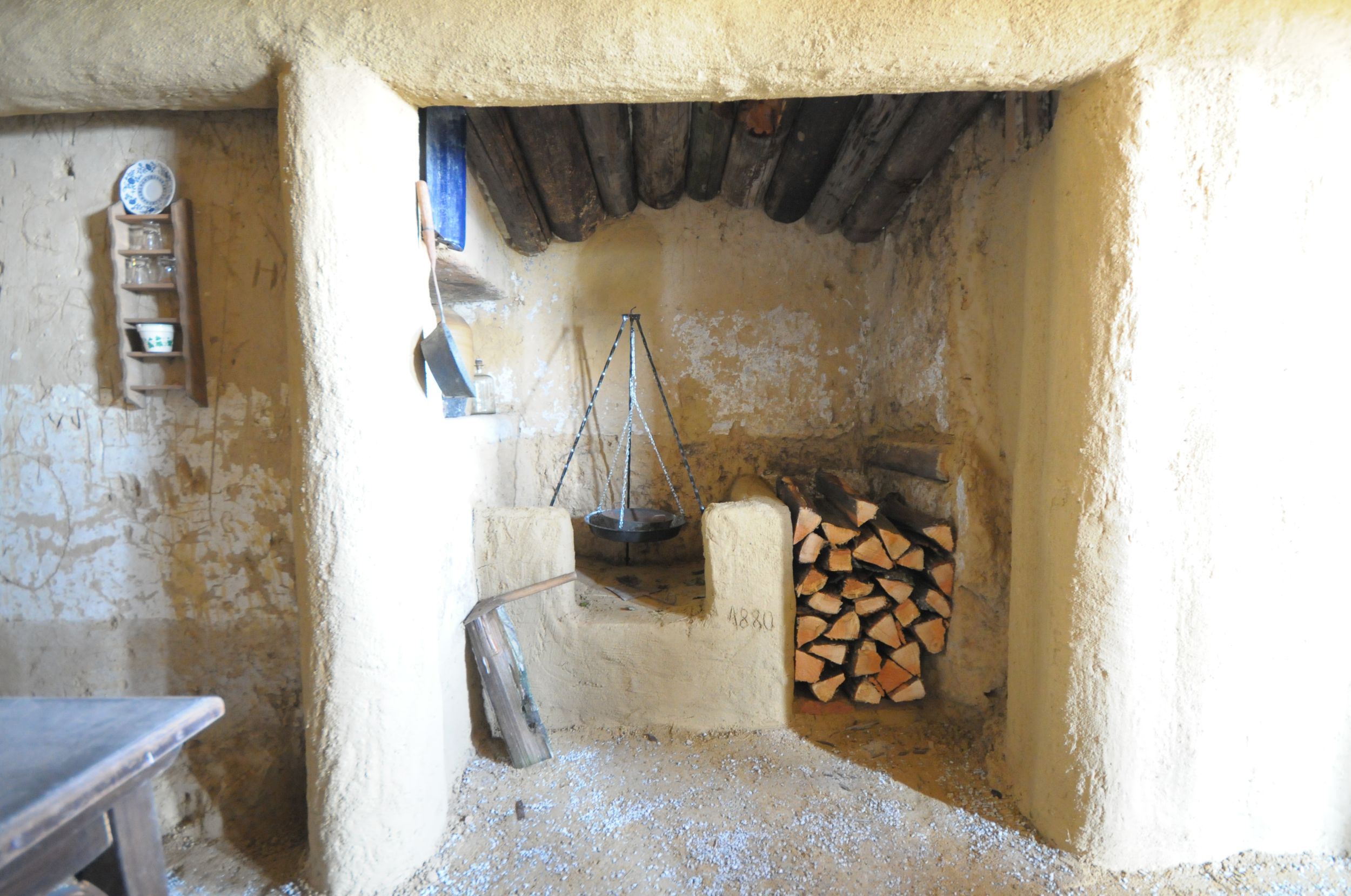 Interior view of a rustic room with fireplace and pile of wood.