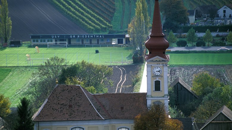 Großriedenthal parish church with church tower and surrounding fields and buildings.
