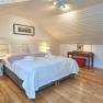 Cozy bedroom with double bed, wooden floor and sloping ceiling.