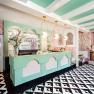 Interior view of a stylish café with pastel-colored decor, geometric floor pattern and a jukebox.