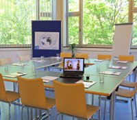 A seminar room with table, chairs, laptop, flipchart and pin board.