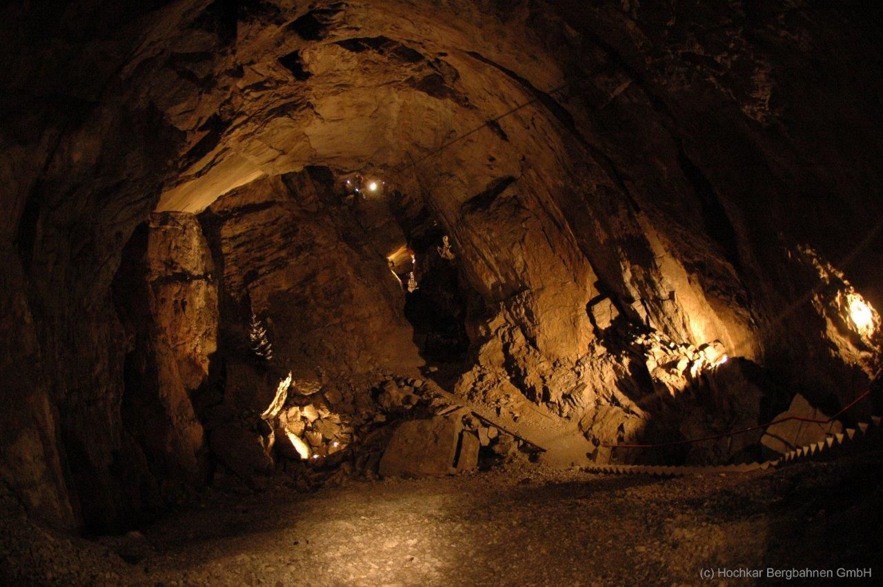 Interior view of an illuminated cave with stony walls and a narrow path.