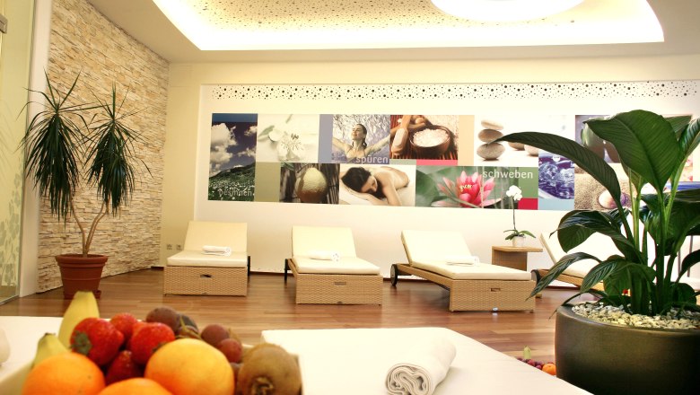 A modern relaxation room with loungers, plants and a fruit bowl in the foreground.