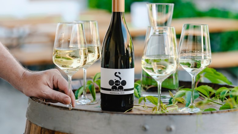 Wine bottle and glasses on a wine barrel outdoors.