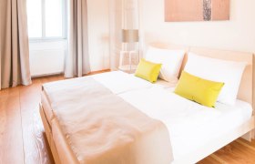 Bright bedroom with double bed, wooden floor and modern lamps.