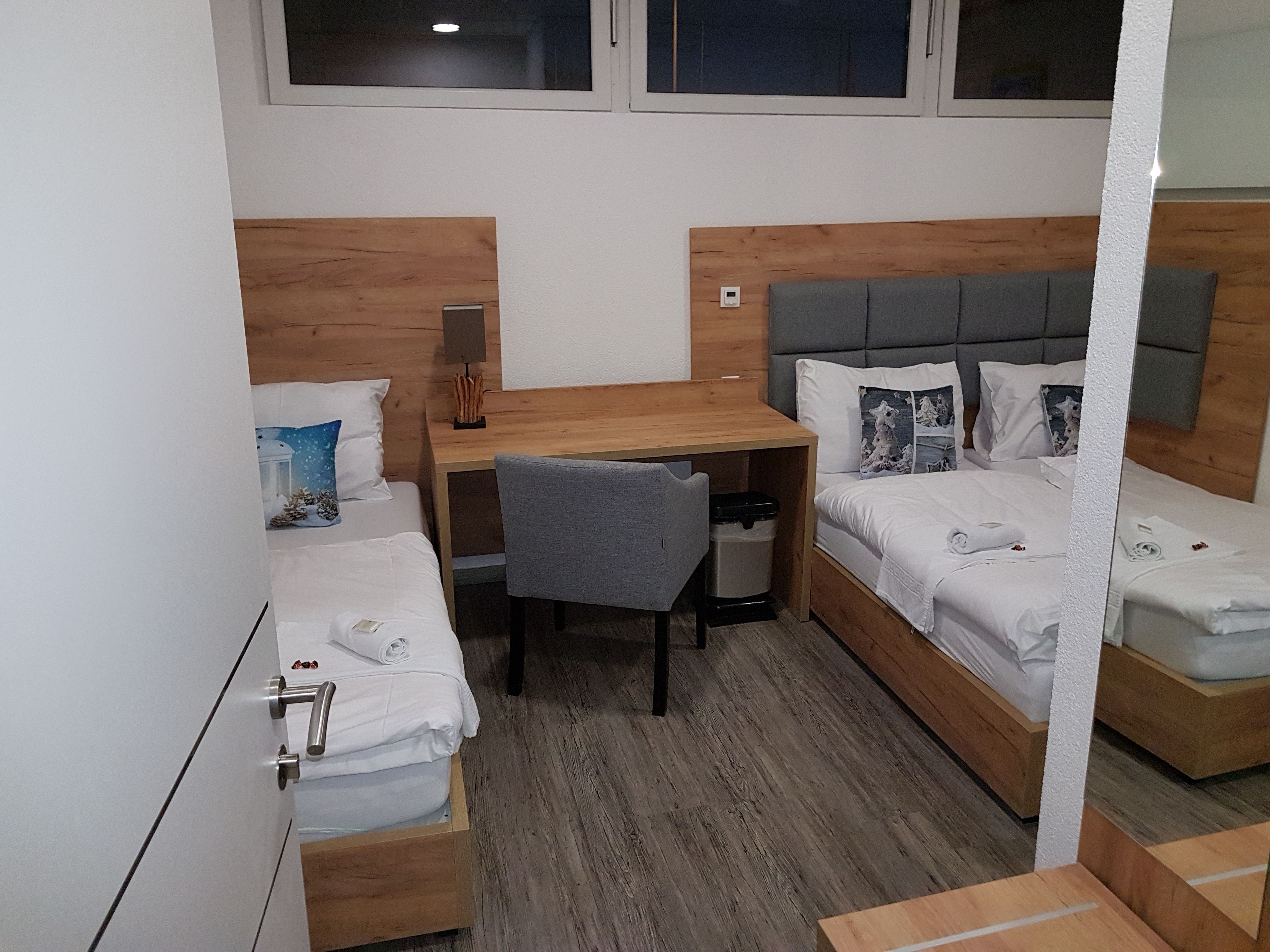 Triple room with two single beds, desk and chair.