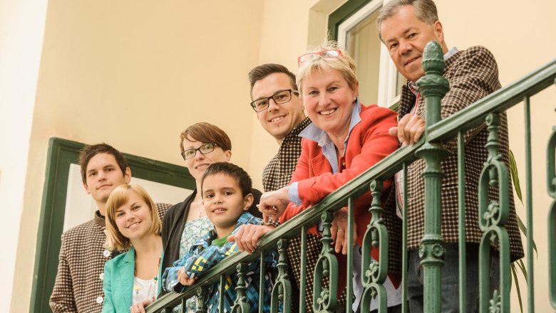 The Gurtner family stands smiling by a green railing on a balcony.