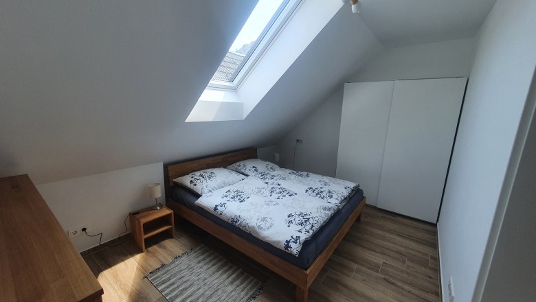 Modern bedroom with skylight, double bed, bedside table and closet.