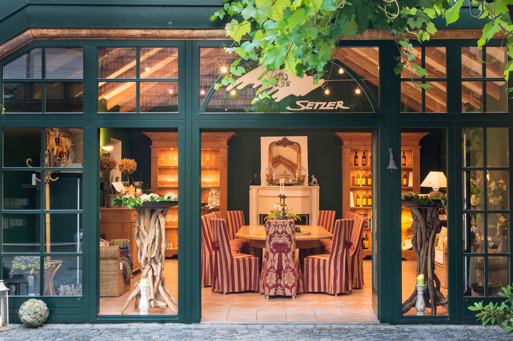 An elegant tasting room with wooden furniture, striped chairs and decorative elements. The room is visible through large windows.