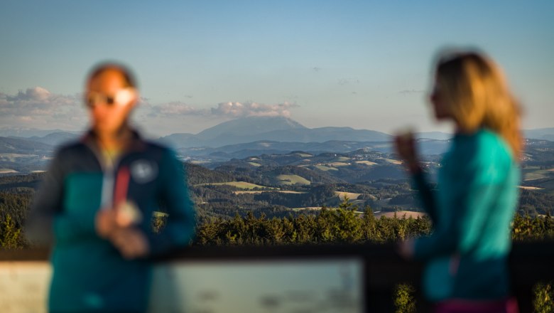 Blurred people in front of a clear mountain landscape in the background. You can see the Schneeberg