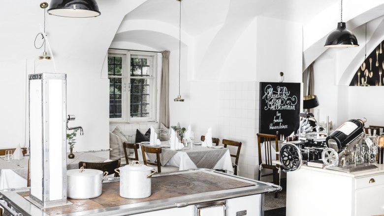 Bright restaurant interior with white walls, wooden furniture and an old stove.