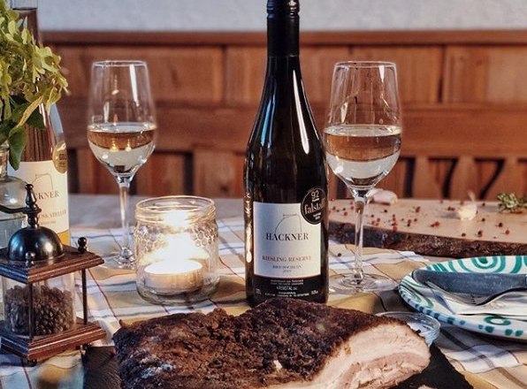 Table with wine bottle, two glasses, candle and meat dish.