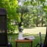 Two deckchairs in the garden with a table on which there is a vase of flowers and a book.
