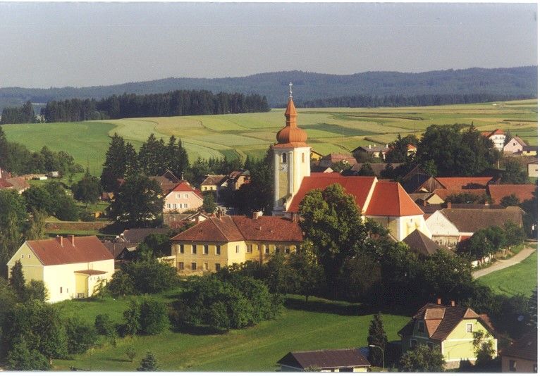 Aerial view of Waldkirchen an der Thaya with church and surrounding houses, surrounded by fields and forests.