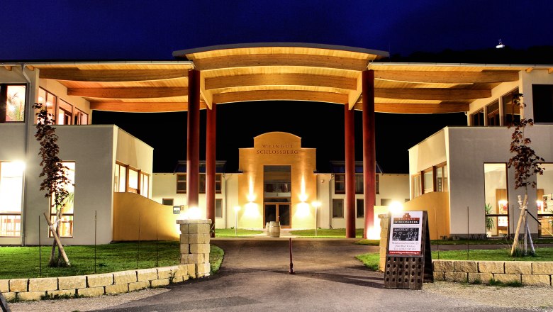 Illuminated building of the Schlossberg winery at night.