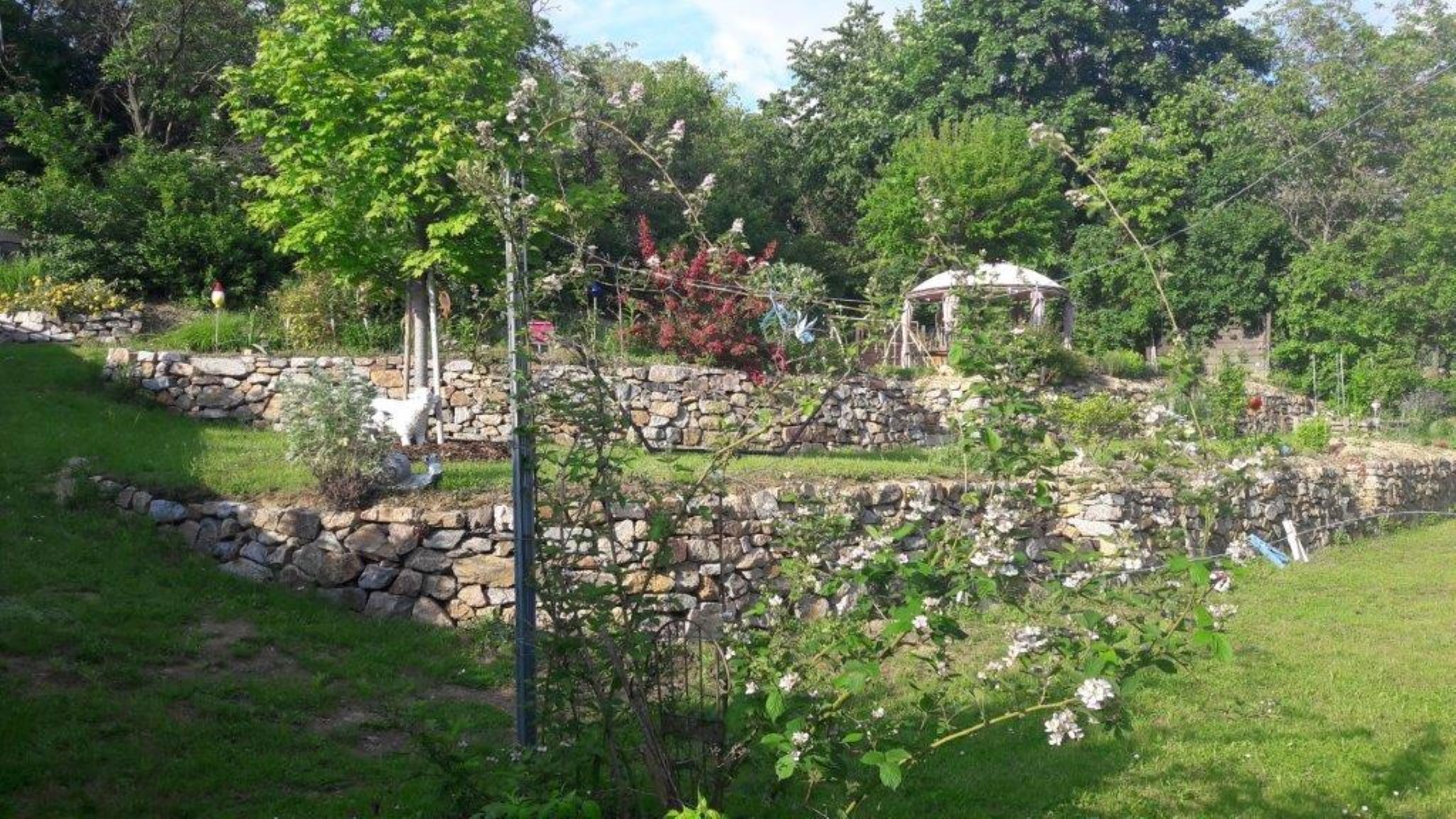 Terraced garden with stone walls and pavilion.
