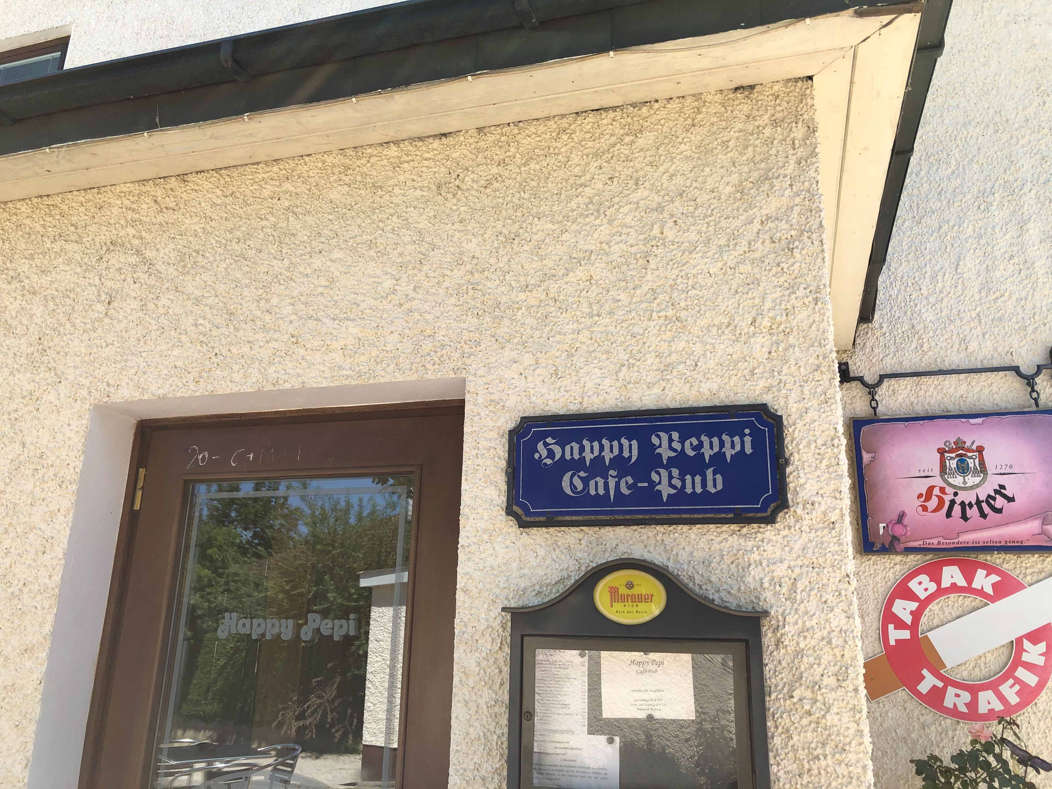 Entrance to the Happy Pepi café-pub with signs and menu on the wall.