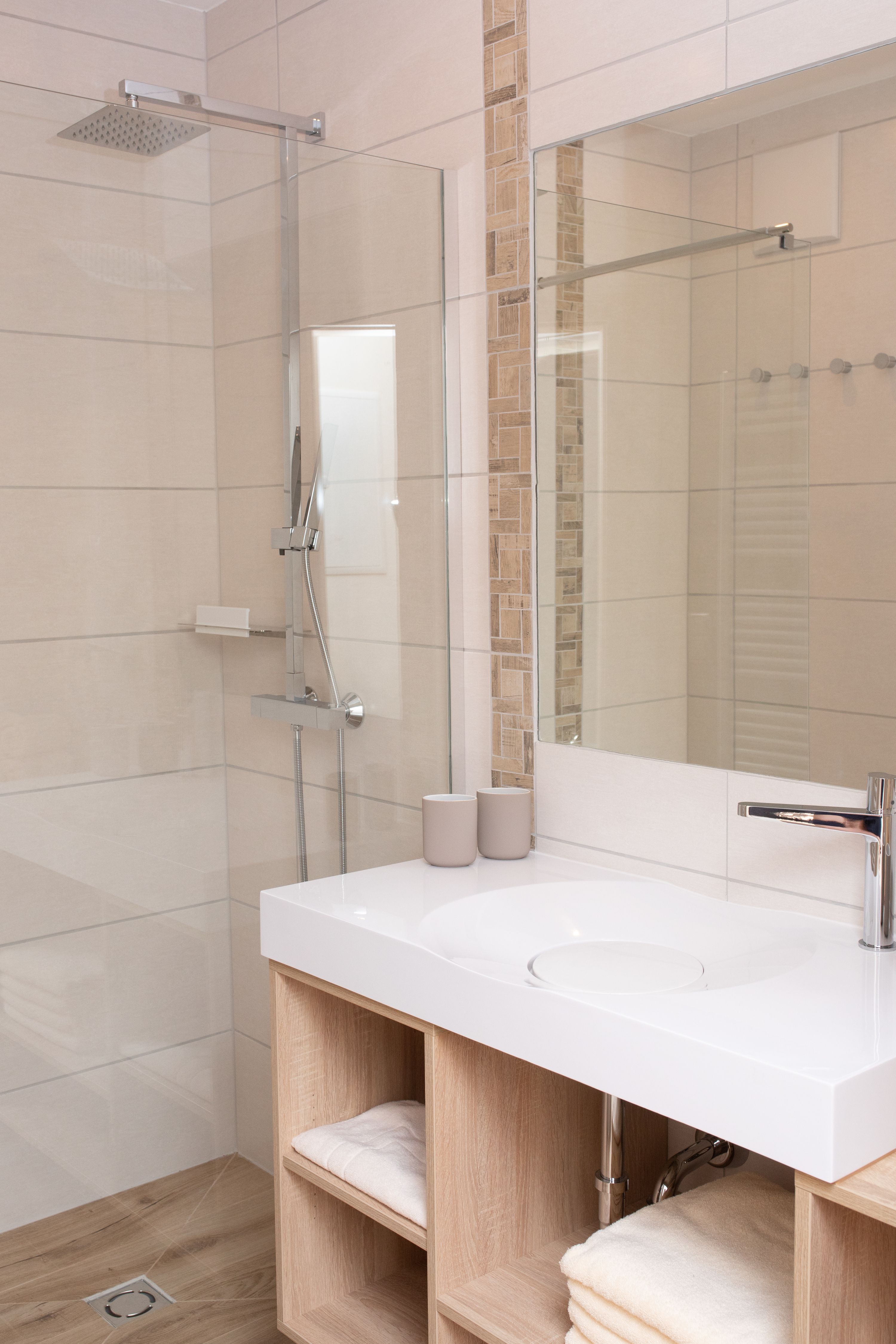 Modern bathroom with shower, washbasin and towels.