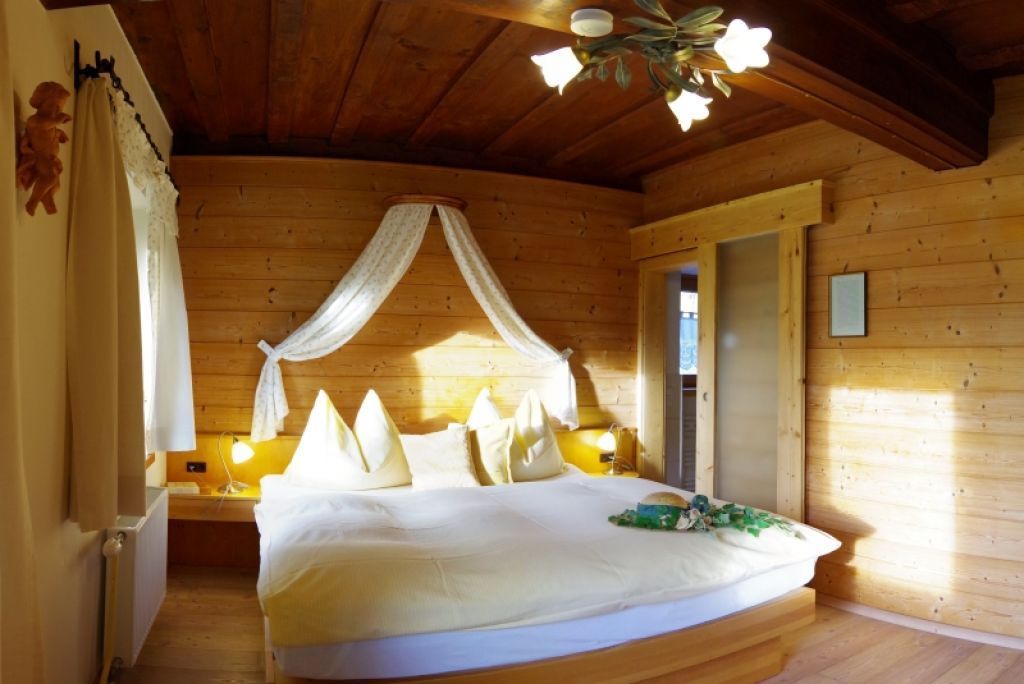 Cozy bedroom with wooden walls and double bed.