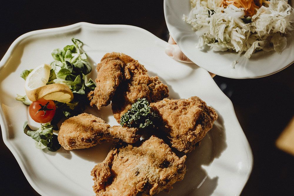 A plate with breaded fried chicken, salad and lemon.