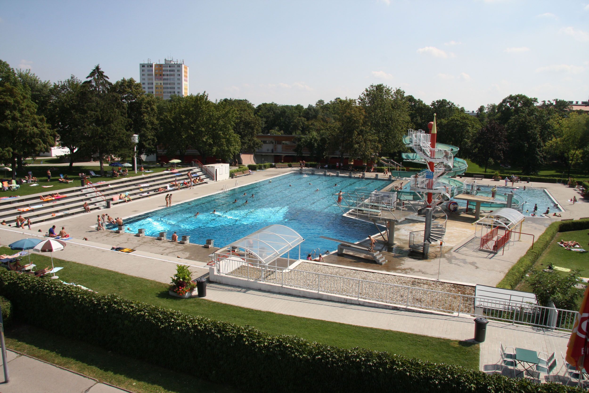 Outdoor pool with swimming pool, water slide and sunbathing lawn.