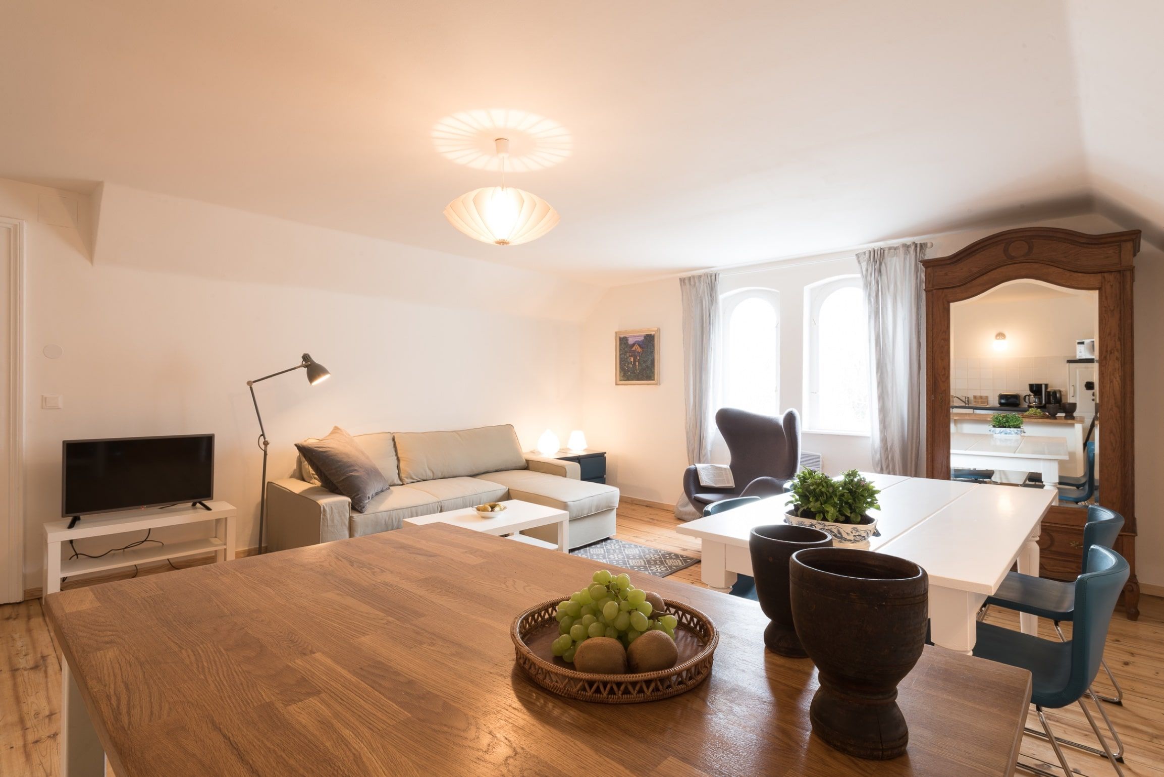 Modern living room with sofa, dining table and mirror.